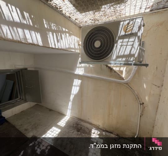 יחידת מיזוג אוויר מותקנת על קיר חיצוני עם צינורות מחוברים